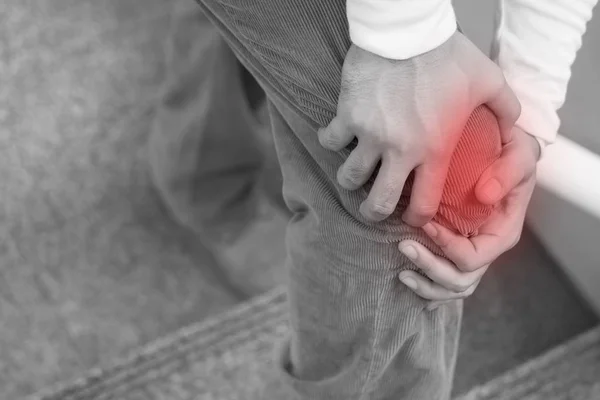 Hombre mano celebración dolor en las articulaciones de la rodilla, exceso de peso que lleva conc — Foto de Stock