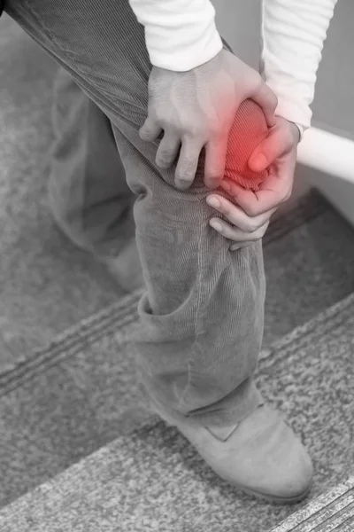 Hombre mano celebración dolor en las articulaciones de la rodilla, exceso de peso que lleva conc — Foto de Stock