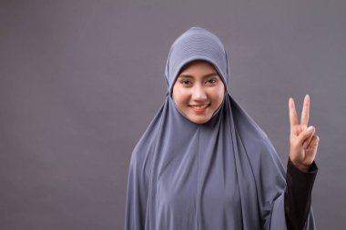 Asyalı Müslüman kadın modeli sayısı 2 kadar zafer el hareketi işaret eden kadın