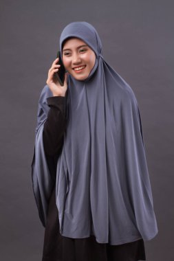 akıllı telefon çağrısıyla mutlu gülümseyen Müslüman kadın