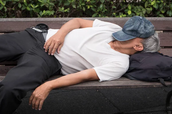 old senior poor homeless man sleeping outdoor, urban poverty concept