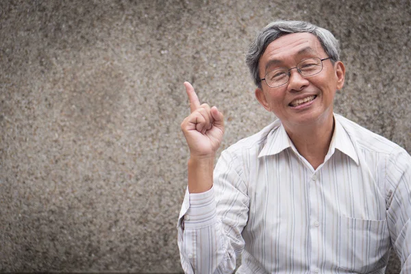 happy old man pointing up one finger, smiling senior, positive retired pensioner portrait