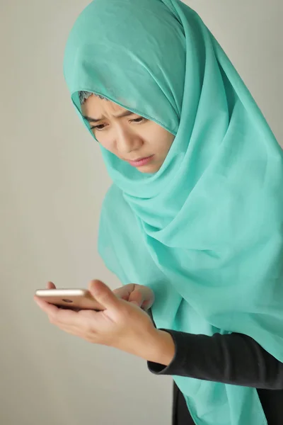 sad, upset, frustrated muslim woman with smart phone