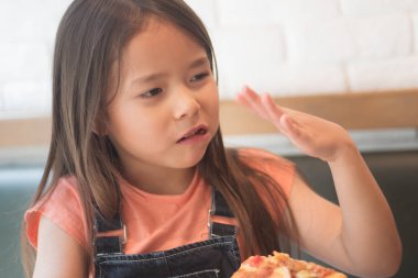 Tatlı küçük kız bir dilim acı ve baharatlı pizza yiyor.