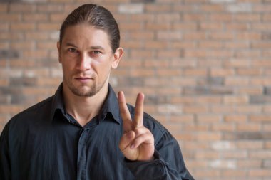 Kendine güvenen beyaz iş adamı V işaretini işaret ediyor 2 parmak; kazanan, kazanan, zafer, aşk, lider, iki puan