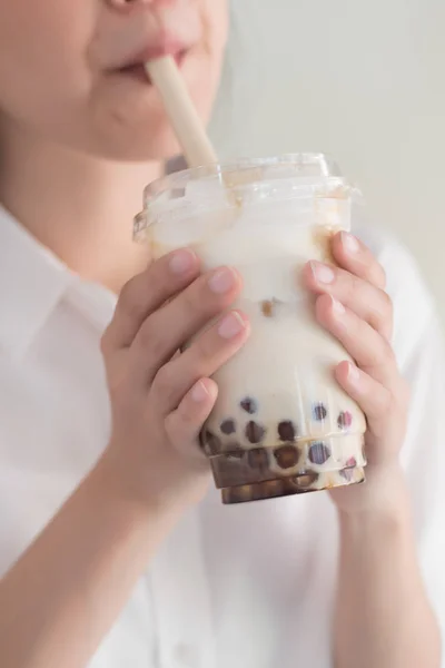 Asian woman drinking iced bubble milk tea; aka boba tea, pearl milk tea, tapioca tea, asian exotic beverage concept