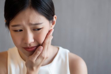 kadın diş ağrısı ile; hasta Asyalı kadın acı diş ağrısı, diş çürüğü, diş hassasiyeti, çürük, diş bakımı kavramı; Genç Yetişkin Asyalı kadın modeli