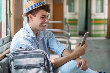Mutlu erkek gezgin akıllı telefon ya da cep telefonu uygulaması kullanıyor, tatilde akıllı telefon aygıtı kavramı