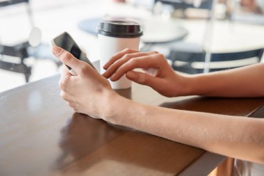 Kadın akıllı telefonu tutuyor, kafede ya da kafede çalışıyor ya da internet bağlantısı kullanıyor. Modern çalışan kadın konsepti serbest çalışan, yüksek teknoloji yaşam tarzı