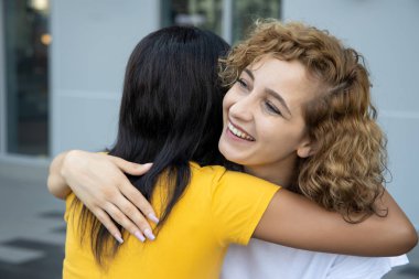 Kafkas beyaz kadın arkadaşına sarılan Afrikalı siyahi kadın; ten rengi toleransı, dünya barışı, etnik köken anlayışı, farklı ten rengi ve etnik kökeni olan uluslararası kadın arkadaşlar