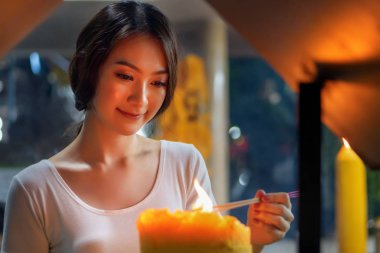 Dindar Asyalı Budist kadın dua ediyor ve tütsü tütsüsü yakıyor. Dişi Budist müridi, meditasyon yapıyor, tütsü yakıyor, tütsü yakıyor tapınakta ya da manastırda dini ayin için alevlerle tütsü yakıyor.