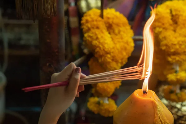 Religious Asian buddhist woman pray and light up joss stick incense. Female buddhist disciple meditating, burning incense fragrance joss stick with flame for religious service in temple or monastery