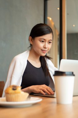 Mutlu Asyalı iş kadını, kahve dükkanında dizüstü bilgisayarla çalışan küçük işletme sahibi; küçük işletme, yeni nesil iş sahibi, çalışan kadın kavramı