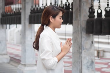 Dindar Asyalı Budist kadın dua ediyor. Dişi Budist müridi, meditasyon yapıyor, tapınaktaki Buda heykeline dua ederek ilahi söylüyor, Güneydoğu Asya Dheravada Budizmi tarzında.