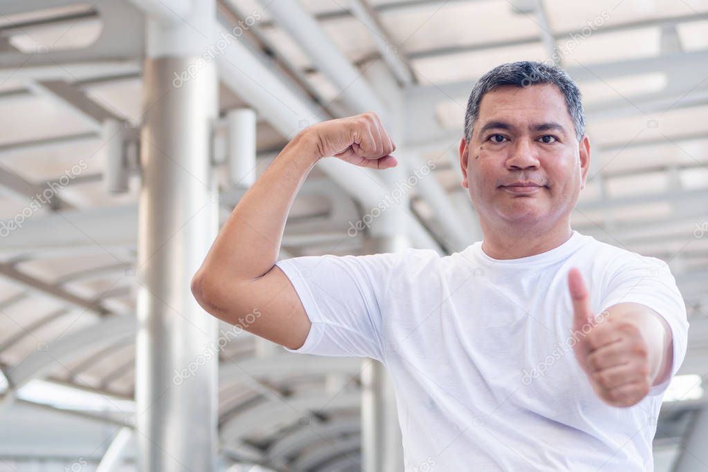 strong and healthy old senior man portrait giving thumb up gesture; strong happy healthy asian senior man in city environment; senior old man model for senior citizen, pensioner, retired man concept