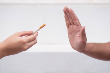 Erkek eli sigara teklifini reddederek sigarayı bırakmaya çalışıyor, sigara dumanına hayır diyor; sigara içmeyi bırakma kavramı, sigara yasağı veya burada sigara içilmemesi.