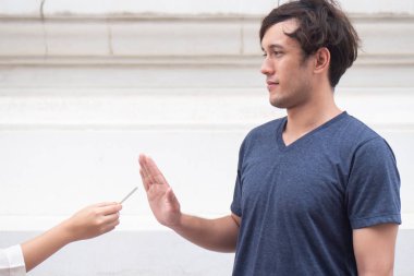 Sigara teklifini reddederek sigarayı bırakmaya çalışan bir adam, sigara dumanına hayır diyerek; sigara içmeyi bırakma kavramı, sigara yasağı veya sigara içilmemesi.