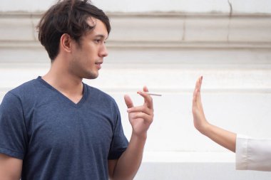 Kadın eli bir erkeği sigara içmekten alıkoyuyor; dur kavramı, sigarayı bırak, sigara içmeyi bırak, sigara içmek yasak