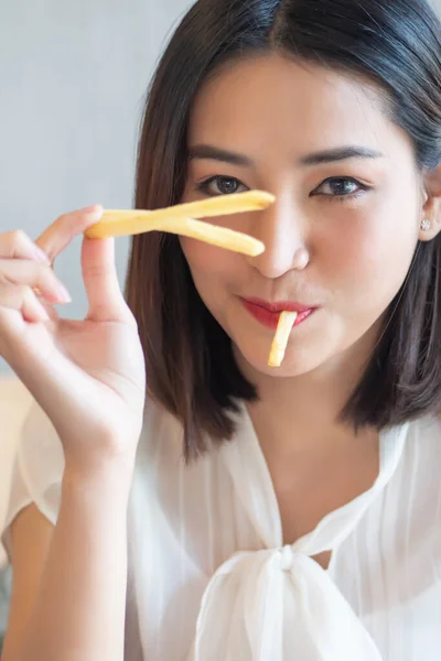 hungry woman looking, eating fried potato, french fries, chips; concept of health care, eating habit, unhealthy junk food, delicious food, fast food