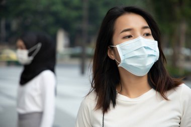 Kirli zehirli dumanla şehirde maske takan kadın; küresel ısınma, emisyon standardı, kirli hava, hava kirliliği, çevre kirliliği, kentsel yaşam sorunu, nefes alma zorluğu