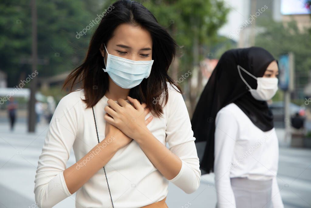 sick woman wearing mask in city with dirty polluted smog; concept of global warming, dirty air, air pollution, allergy sickness, breathing difficulties, sore throat, lung cancer due to air quality