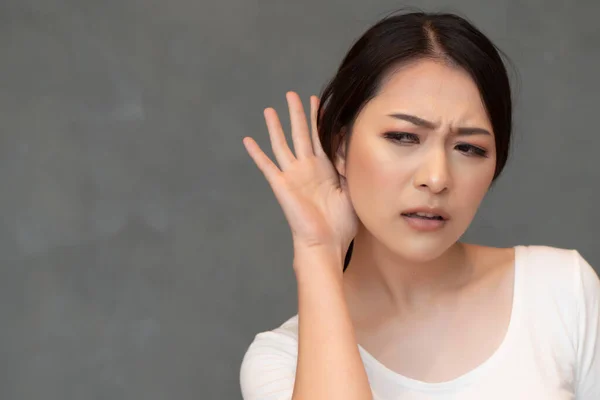 女人听着某事 亚洲女人听着耳朵的画像 流言蜚语 听力丧失 窃窃私语 假新闻 好消息 坏消息 — 图库照片