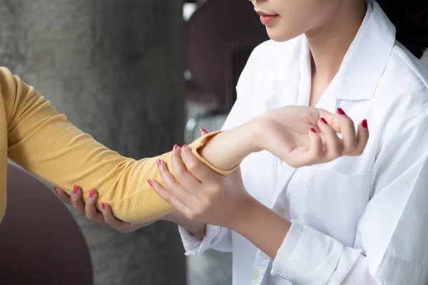 female orthopedic, bone doctor looking into the arm bone or elbow joint of woman patient; concept of dedicated orthopedic surgery, bone doctor test, therapist, medical worker on the job