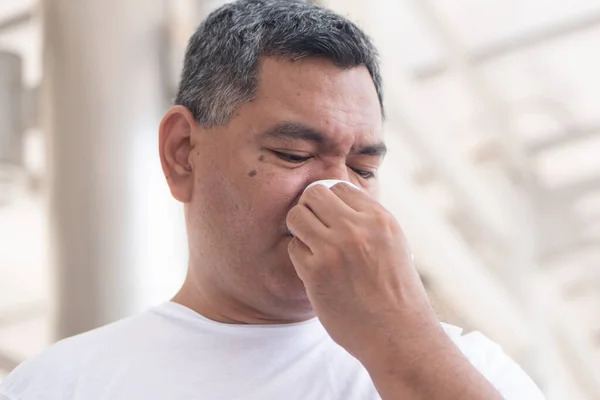 allergic sick old man wiping his runny nose and touching his face; concept of man with coronavirus covid-19 infection disease, allergy, lung inflammation, pneumonia, influenza, flu, cold, sickness