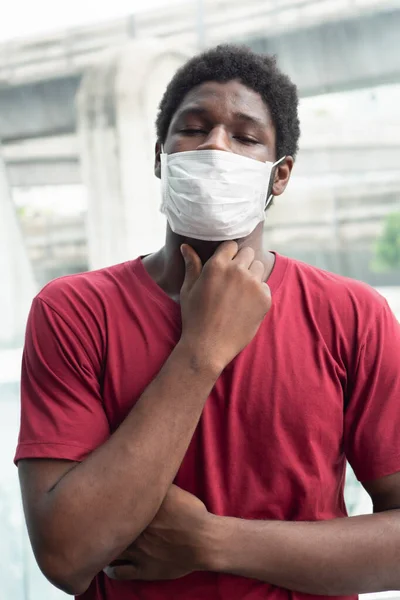 allergic sick black African man coughing with sore throat; concept of african man with allergy, pneumonia, sore throat, lung inflammation, influenza, flu, cold, sickness, social distancing concept