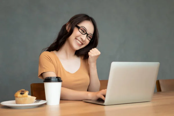 happy asian business woman works from home; woman office worker working at home with laptop computer; business in epidemic crisis, social distancing, physical distancing, working in isolation concept