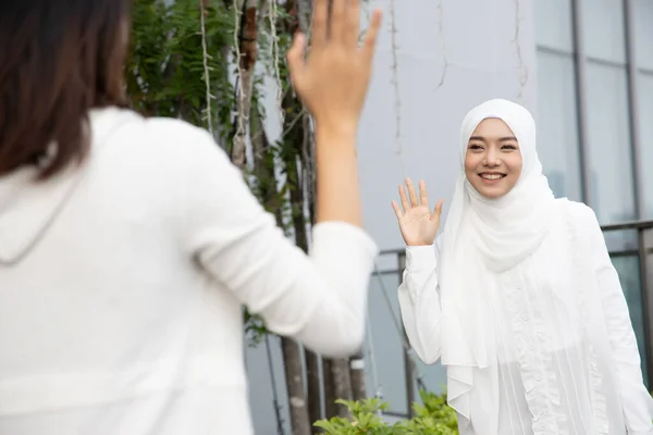 Muslim woman or Muslimah greeting her friend; Concept of friendly Islamic woman, religion of peace, Ramadan, Salam, As-salamu alaykum, Peace be upon you; Asian Muslim young adult woman model