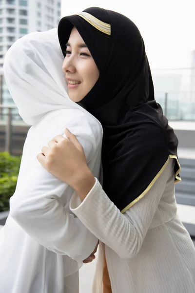 Muslim woman or Muslimah greeting with hug; Concept of Islamic greeting by woman, religion of peace, Ramadan, Salam greeting, As-salamu alaykum, Peace be upon you; Asian Muslim young adult woman model