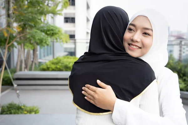 Muslim woman or Muslimah greeting with hug; Concept of Islamic greeting by woman, religion of peace, Ramadan, Salam greeting, As-salamu alaykum, Peace be upon you; Asian Muslim young adult woman model