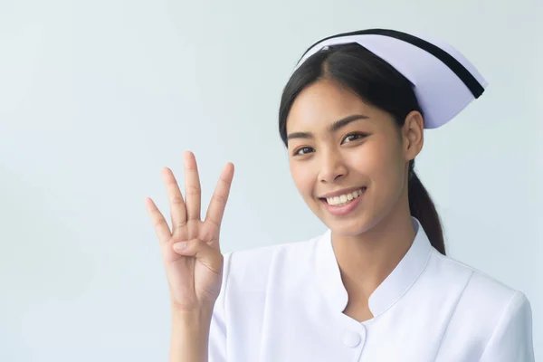 快乐微笑的亚洲女性护士的画像 孤立地将4个手指指向空白处 自信而专业的女性护士或医务工作者将4个手指指向空白处 4个点或4个点 — 图库照片