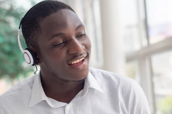 African black man listening to music; portrait of relaxed, carefree African black man with headsets and music player enjoying the song and singing along