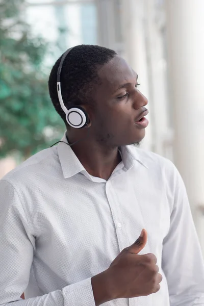 African black man listening to music; portrait of relaxed, carefree African black man with headsets and music player enjoying the song and singing along