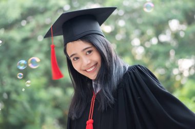 Mutlu gülümseyen üniversite mezunu; başarılı eğitim kavramı, mutlu diploma günü, kadın eğitim eşitliği, iş fırsatı, yüksek öğrenim diploması, denizaşırı burslar