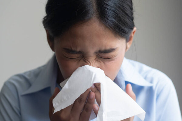 больная женщина чихает с больным горлом; больная женщина с симптомом аллергического чихания, больное горло, простуда, грипп, инфекционные вирусные заболевания, коронавирус, аллергия, концепция здравоохранения; молодая модель взрослой женщины
