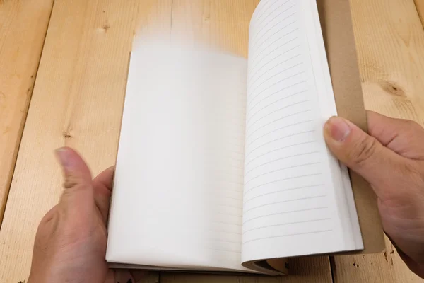 Ręce trzymać książki na stół z drewna — Zdjęcie stockowe