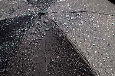 siyah bir şemsiye düşen yağmur damlaları