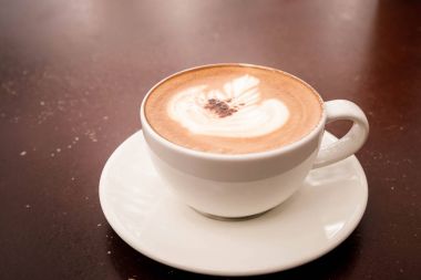  güzel latte sanat sıcak cappuccino ahşap masa kahve fincan ile.