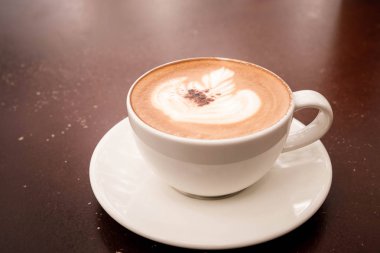  güzel latte sanat sıcak cappuccino ahşap masa kahve fincan ile.