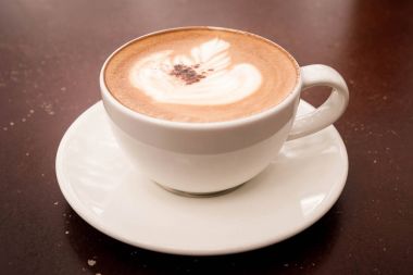  güzel latte sanat sıcak cappuccino ahşap masa kahve fincan ile.