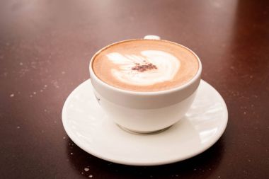  güzel latte sanat sıcak cappuccino ahşap masa kahve fincan ile.