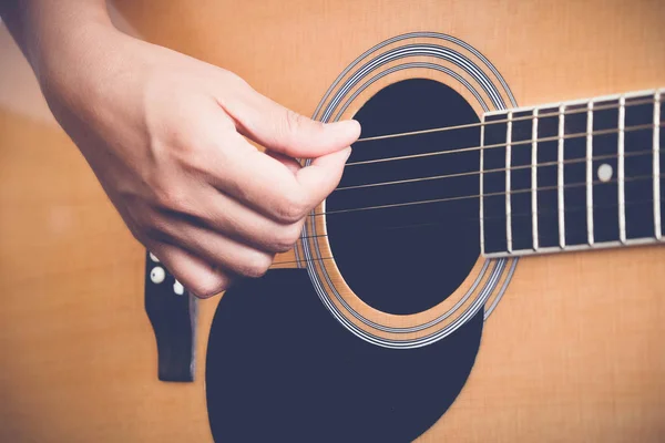 Mains de femme jouant de la guitare acoustique avec effet filtre style vintage rétro — Photo