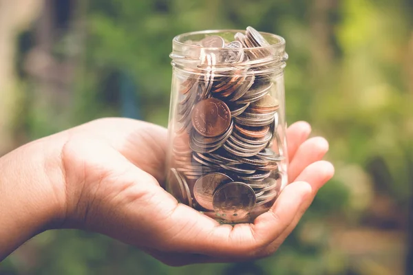 Save money for investment concept Hand holding money in jar with filter effect retro vintage style — Stock Photo, Image