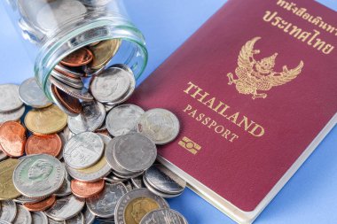 Tayland pasaportu kahverengi kapak ve para sikke üzerinde mavi kağıt arka plan tatil seyahat için