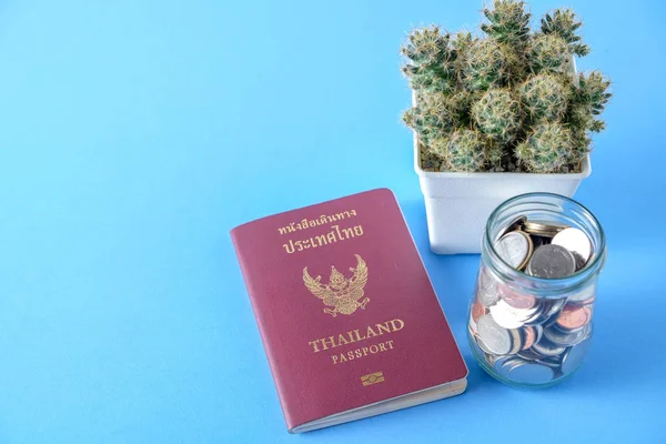 Thailand passport  brown cover and money coin on blue paper background for traveling on holidays