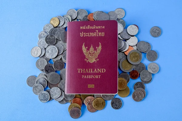 Tailandia pasaporte marrón cubierta y moneda de dinero sobre fondo de papel azul para viajar en vacaciones — Foto de Stock