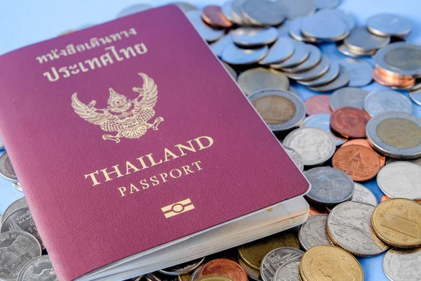 Thailand passport  brown cover and money coin on blue paper background for traveling on holidays